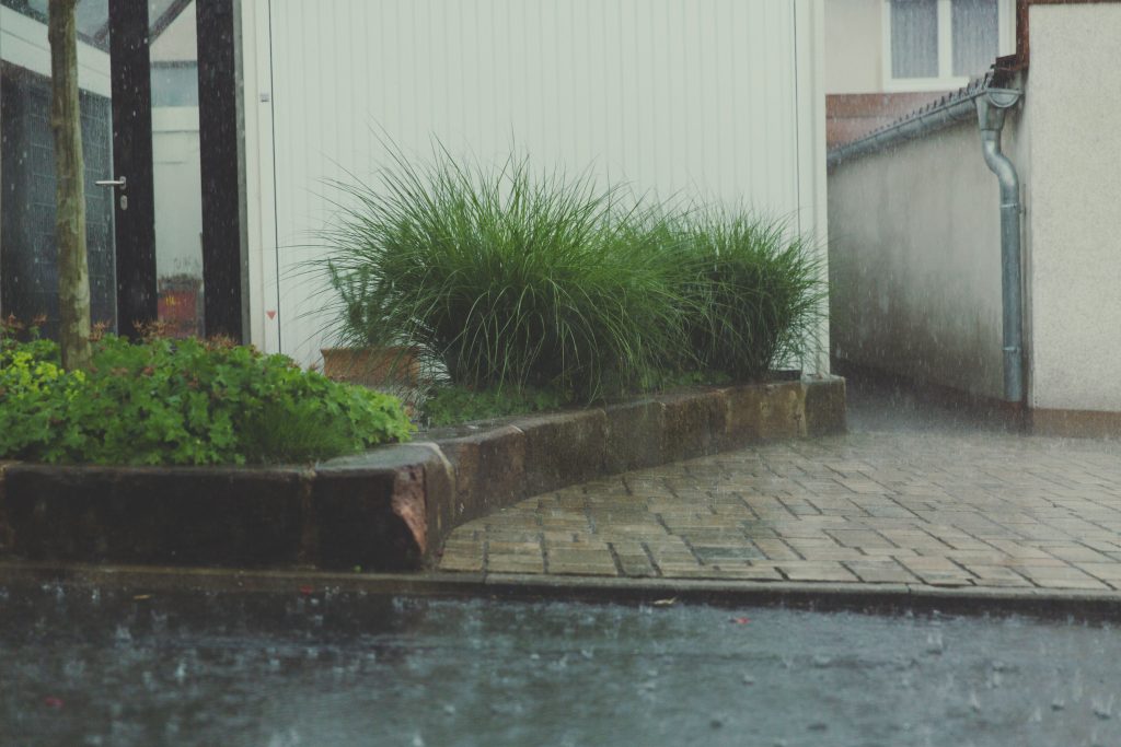Maison à Douala sous pluie intense, façade visible en fond, illustration du contexte climatique